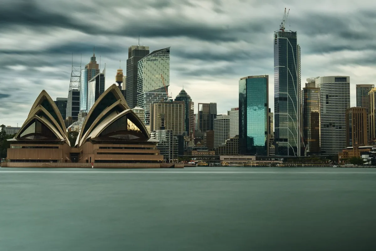 A city skyline with a harbour bridge and boats on the water