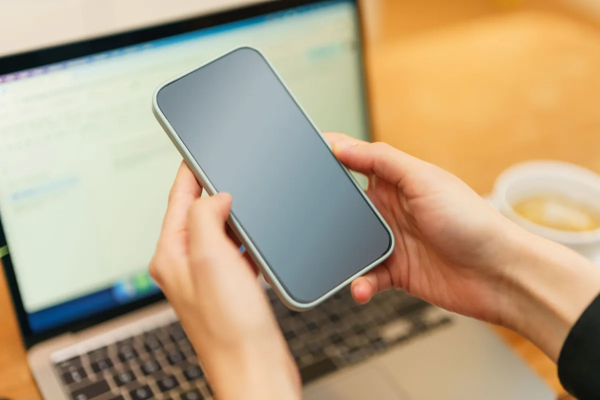 A phone and a laptop on a desk showing a payment confirmation