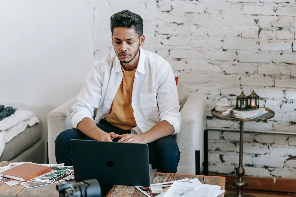 A person typing on a laptop at a desk in a bright living room