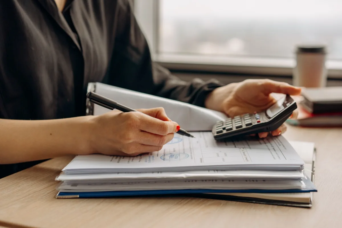 An accountant checking invoice figures with a calculator and documents