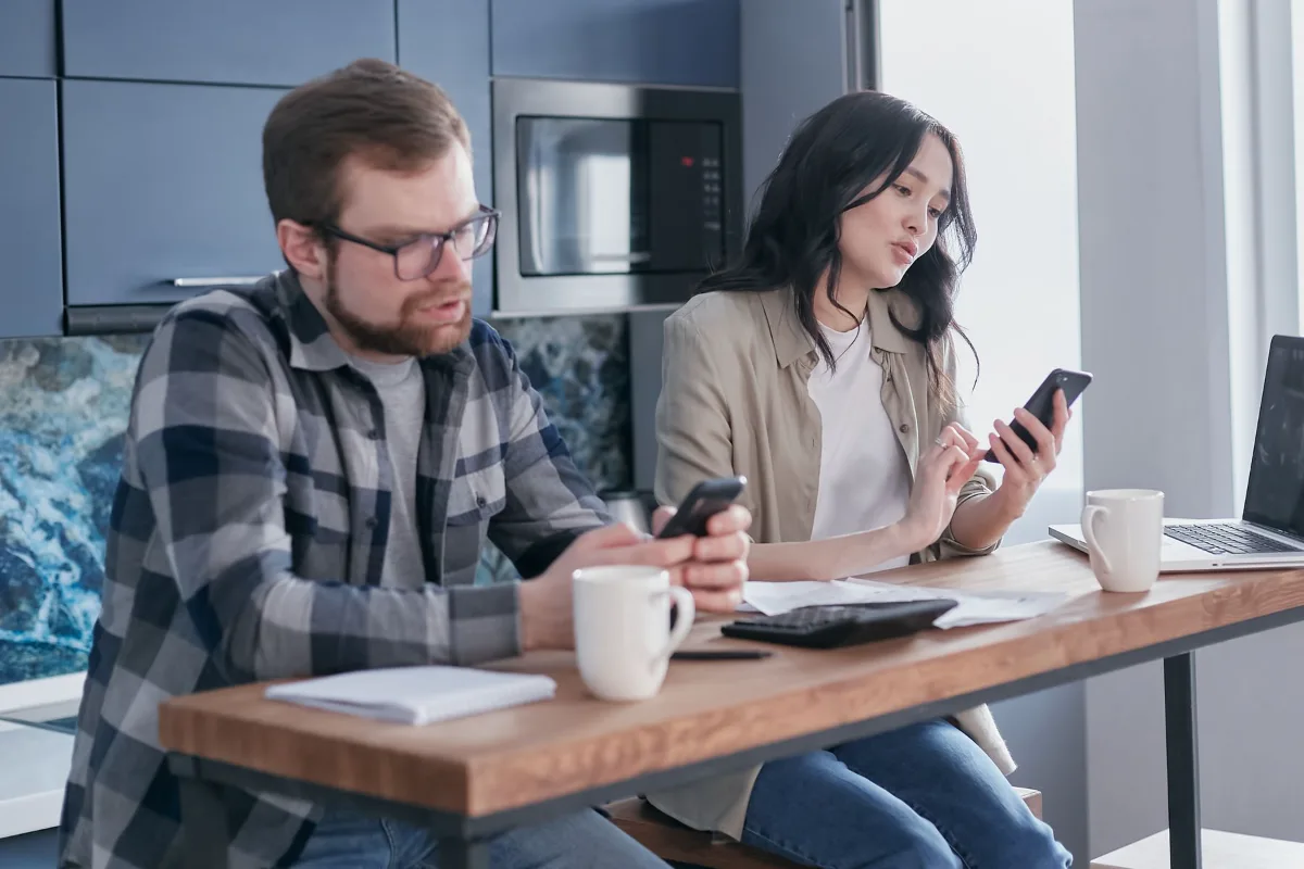 A couple reviewing finances and a calculator at a kitchen table