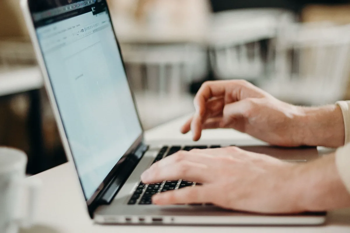 Hands typing an email on a laptop at a table
