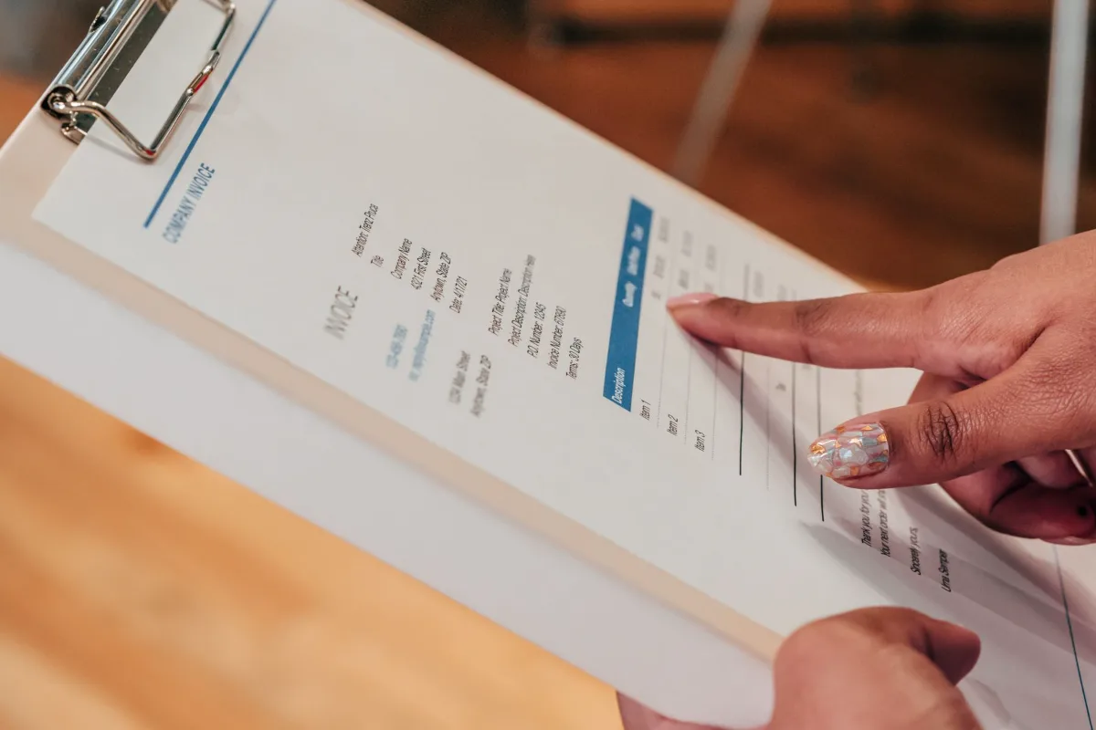 Two people pointing at figures on an invoice attached to a clipboard