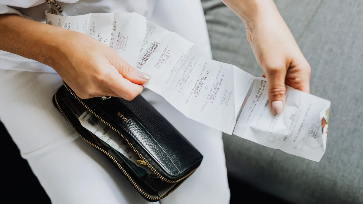 A woman's hands holding several paper receipts