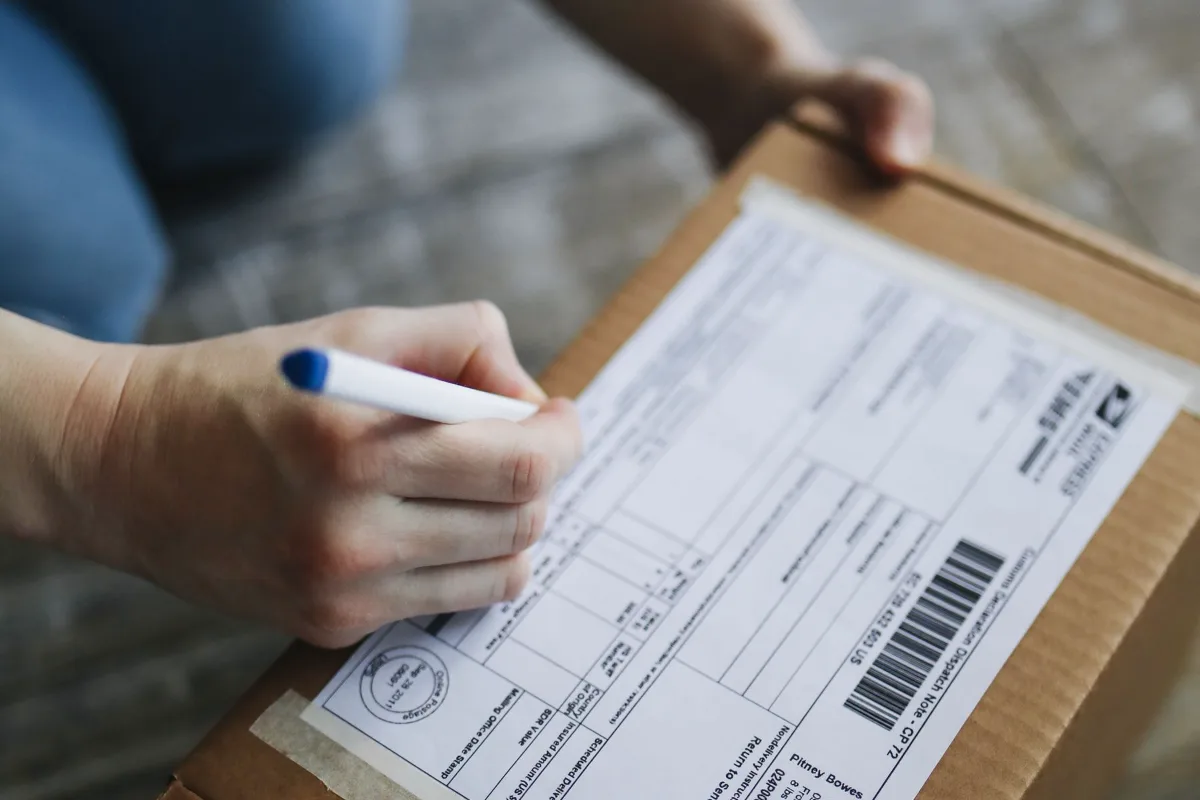 Hands filling in a shipping label on a parcel