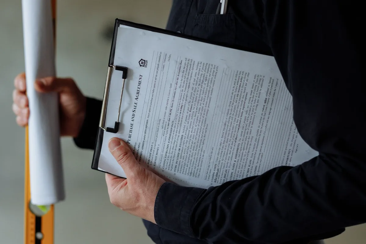 An architect holding a clipboard with documents and rolled blueprints