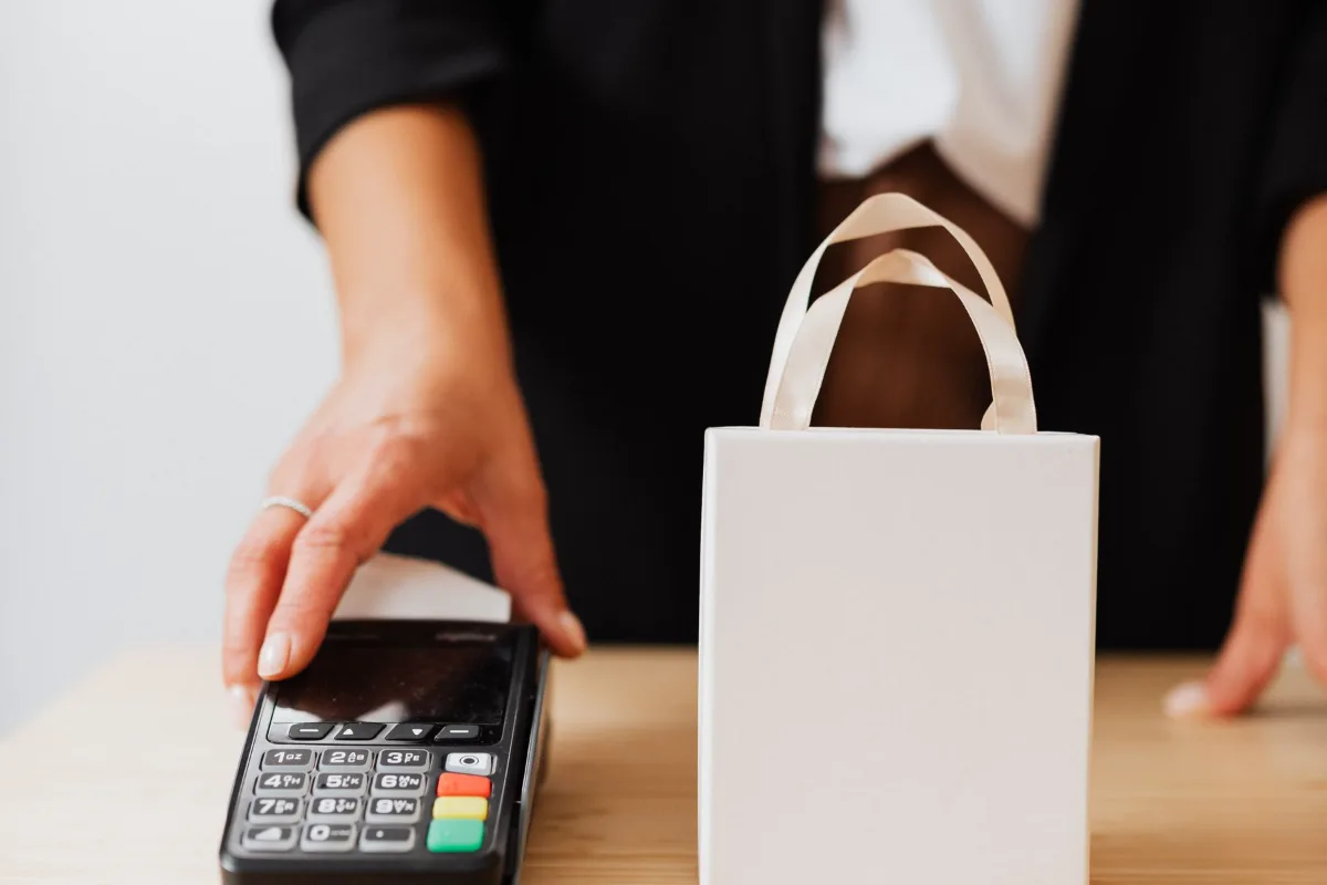 A card payment being made at a shop counter next to a bag