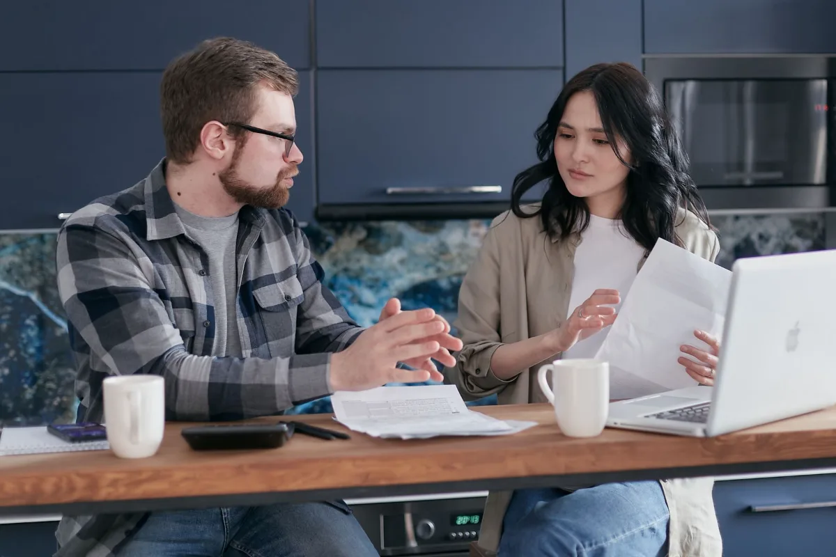 Two colleagues checking figures and paperwork at a table