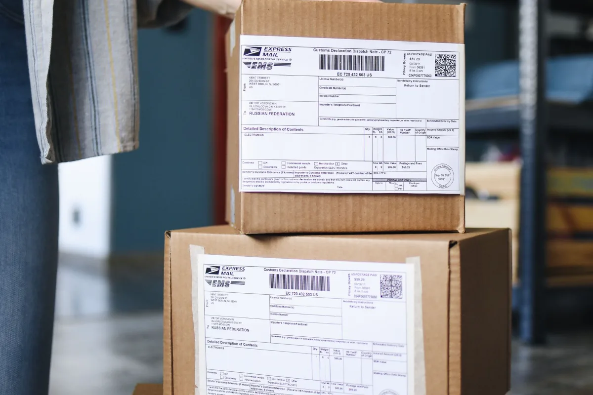 A courier checking a delivery against a clipboard next to boxes