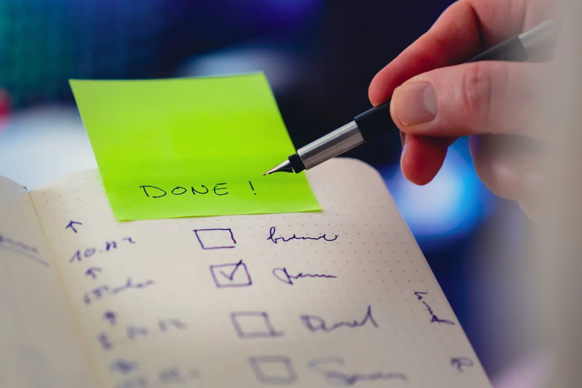 A hand writing a checklist with checkboxes in a notebook
